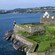 A centuries old stone fortification with grassy banks situated along a rocky shoreline